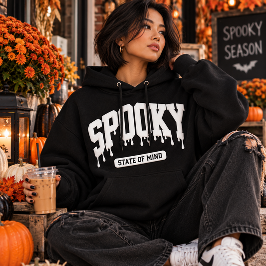 Korean woman with short dark hair wearing a black Spooky State of Mind puff vinyl hoodie in an autumn Halloween setting