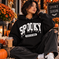 Korean woman with short dark hair wearing a black Spooky State of Mind puff vinyl hoodie in an autumn Halloween setting